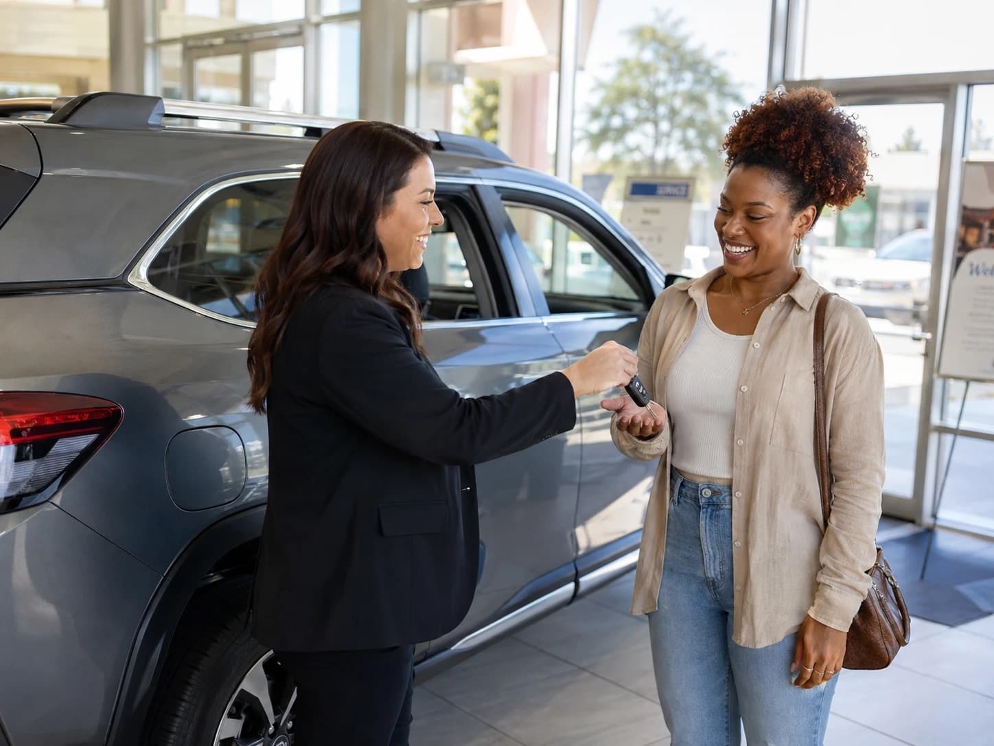Salesperson handing keys to a customer in a dealership showroom